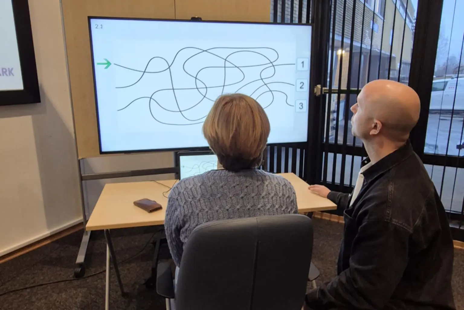 Demonstrasjon av det databaserte synstreningsprogrammet VisionBuilder som brukes til synsrehabilitering her på sykehuset. To personer sitter foran PC-en