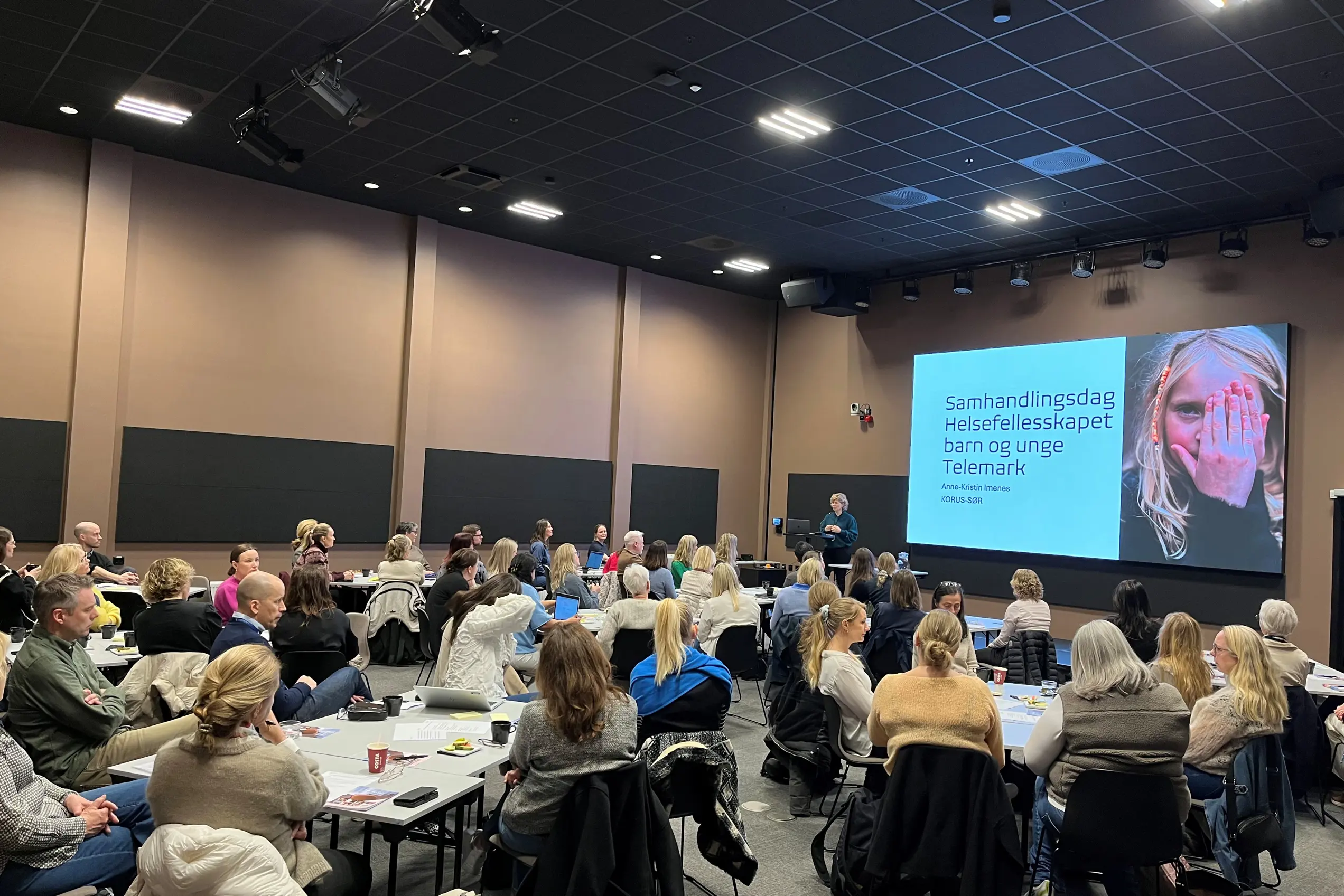 En gruppe mennesker som sitter i et rom og ser på en skjerm