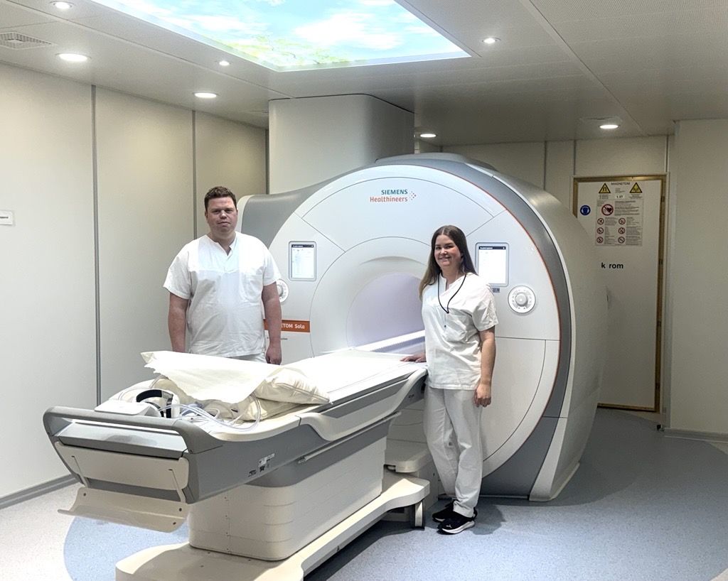 To ansatte ved Sykehuset står ved siden av en ny MR-maskin