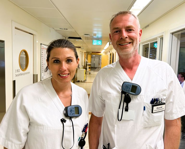 En mann og en kvinne iført hvite labfrakker og smilende