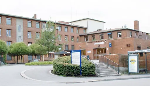 En bygning med trær og busker foran seg