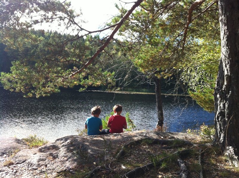 Illustrasjonsfoto - to barn som sitter med ryggen til og ser utover vannet