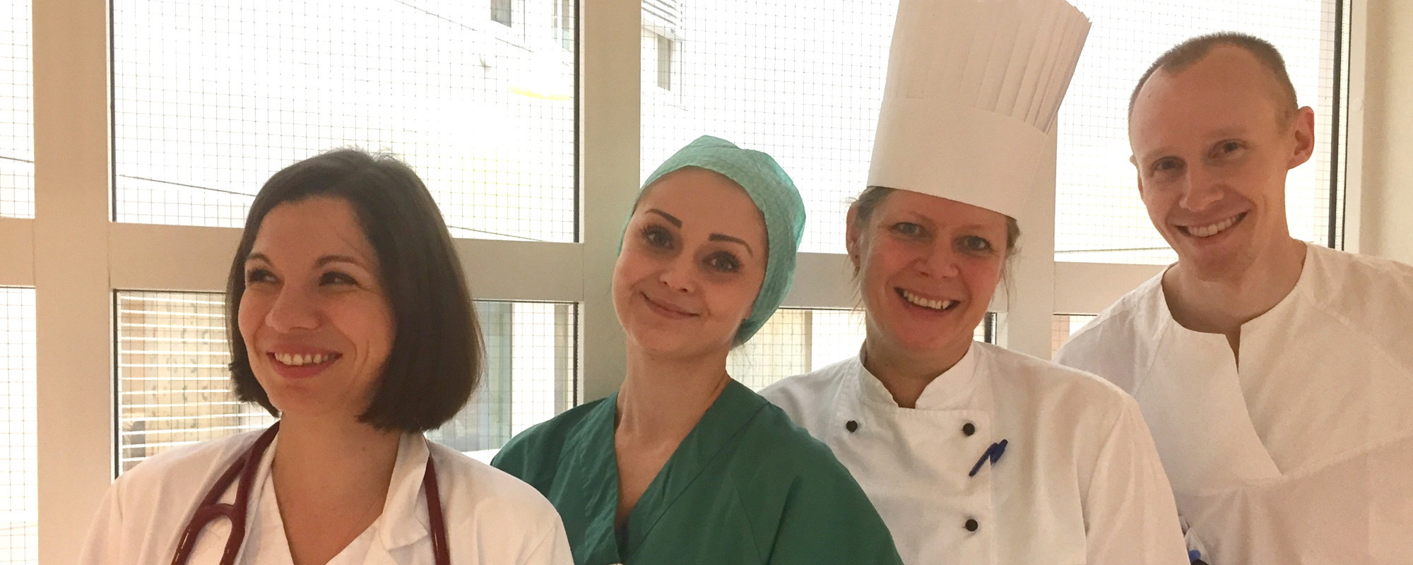 En gruppe mennesker iført hvite labfrakker og smilende