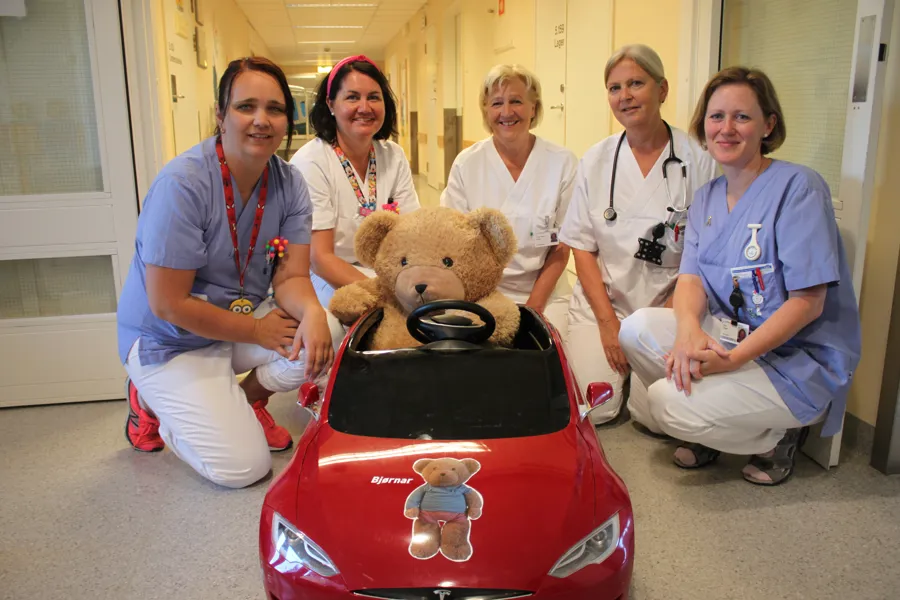 A group of women posing with a teddy bear