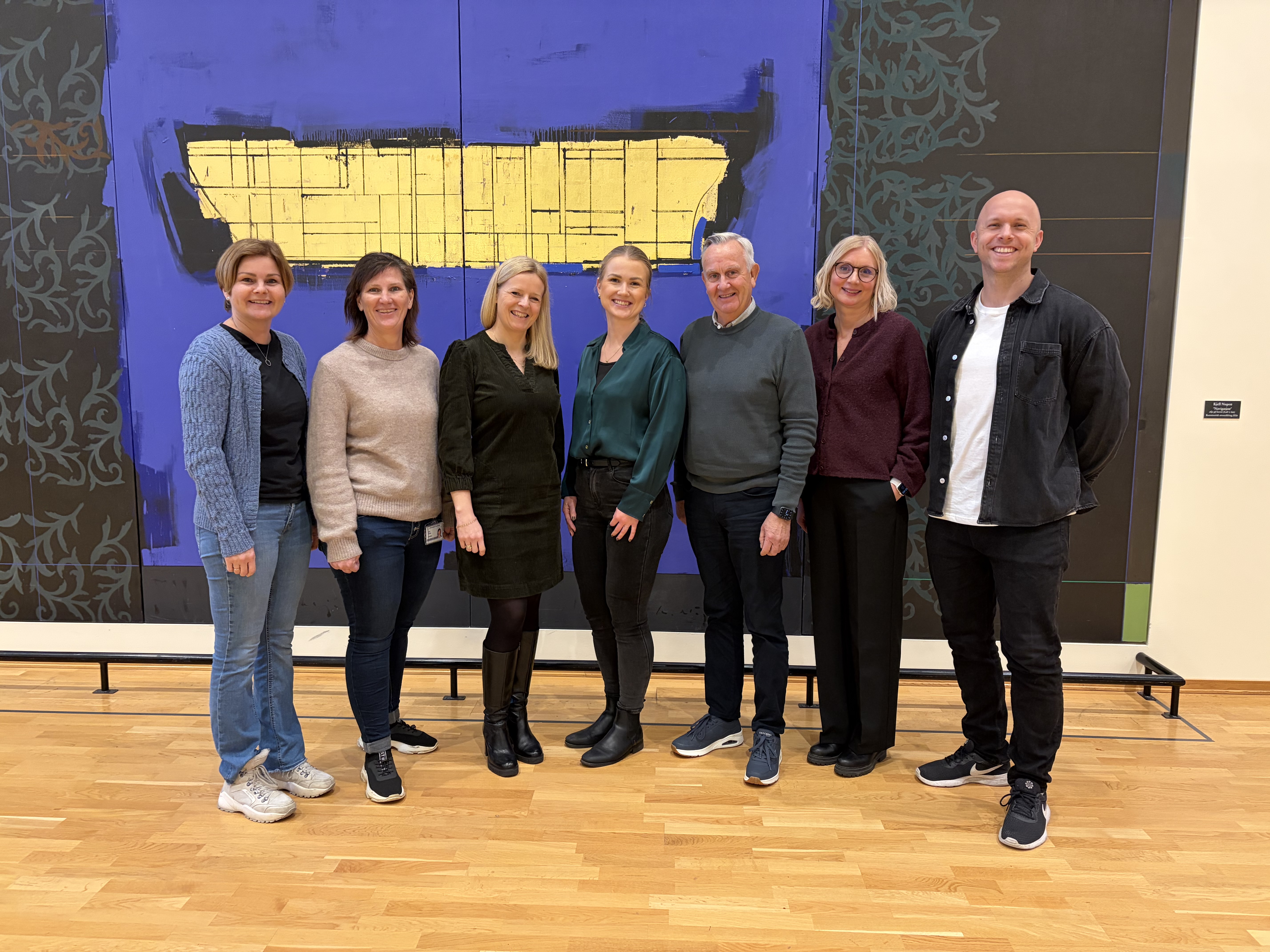 Bilde av syv i nettverket foran en vegg inne på sykehuset