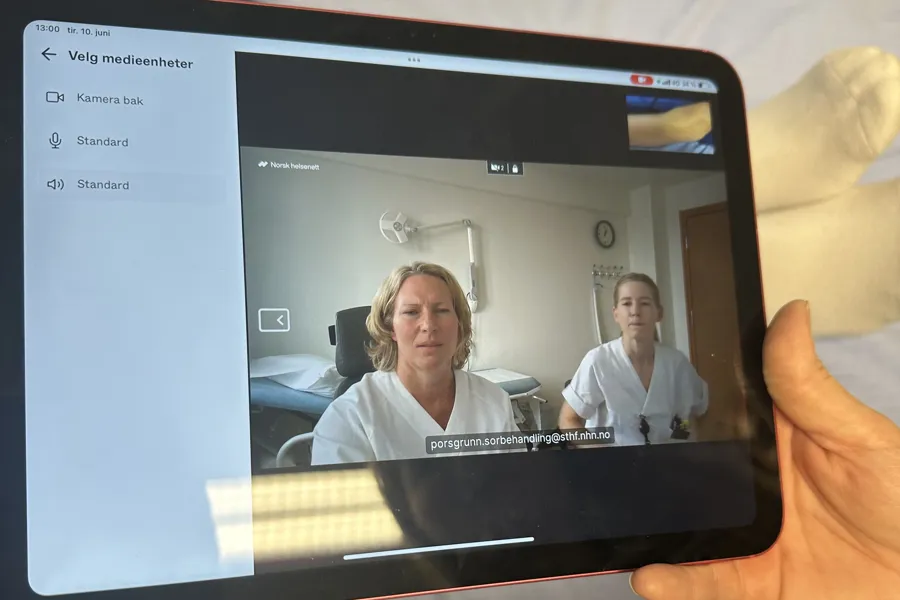 En person som holder en ipad, hvor sårbehandlingen foregår. På ipaden ser man to fra sykehuset.